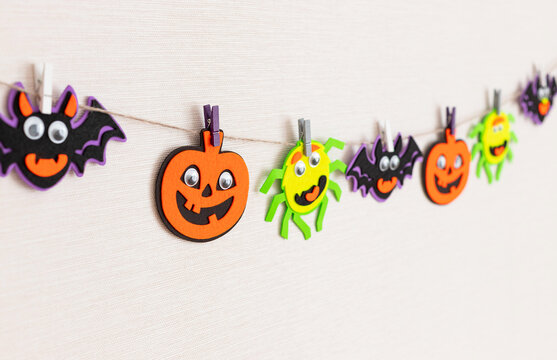 Halloween decoration on wall, felt monsters garland with scary faces. Handmade decoration for festival party. selective focus