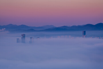 Scenic view of the city under the fog during sunrise