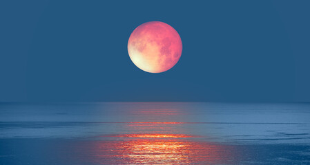 Lunar eclipse with calm sea at sunset 