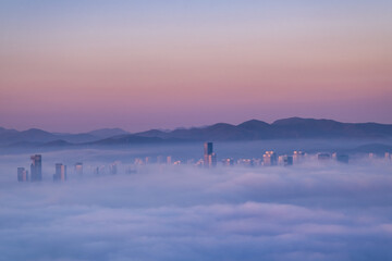 Scenic view of the city under the fog during sunrise