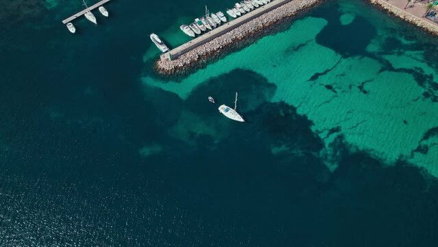 View from above of Fornells village located in a bay in the north of the Menorca 
Drone view of a harbour filled with llauts, the traditional Menorcan fishing craft, surrounded by white washed houses.