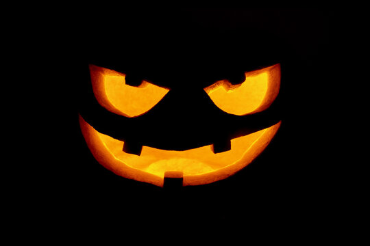 Traditional scary jack-o'-lantern smiling face glowing in the dark, made from a pumpkin to celebrate the Halloween holiday. 