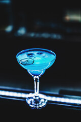Blue lagoon cocktail with blue curacao liqueur, vodka, lime juice and soda on bar counter