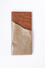 Chocolate bar in opened pack on white table background. Closeup