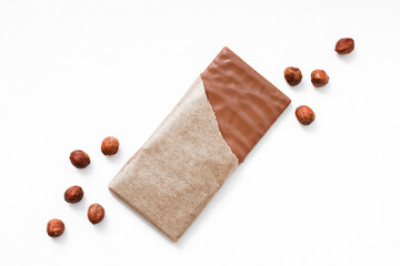 Flat lay composition with opened chocolate bar with hazelnuts on white background