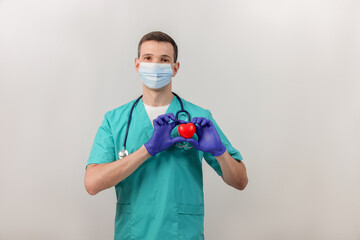 Male cardiologist  in a mask and gloves with stethoscope  with heart. Doctor is holding a red...