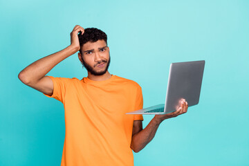 Photo of minded clueless person hold netbook arm scratch head isolated on turquoise color background