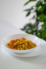 Italian pasta with shrimp and turmeric on a white table in a white plate