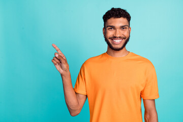 Fototapeta premium Photo of sweet good mood man dressed orange t-shirt pointing finger empty space isolated turquoise color background