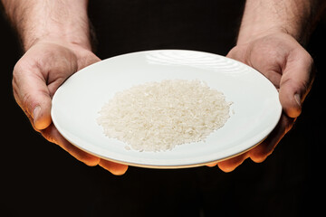 Hands holding a heap of dry rice grain on black background