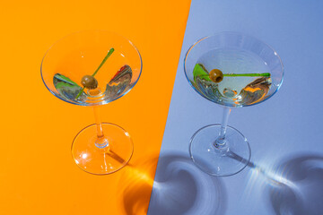 Two classic dry martini with olives on color background.