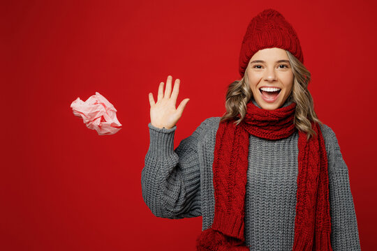 Young Happy Health Woman Wears Grey Sweater Scarf Hat Throw Away Pink Napkin Tissue Isolated On Plain Red Background Studio Portrait Healthy Lifestyle Ill Sick Disease Treatment Cold Season Concept.