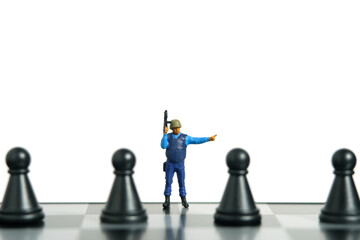 Miniature people toy figure photography. Protection strategy concept. A security officer standing above chessboard. Isolated on white background.