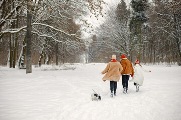 Backside photo of teen siblings and their mother having fun at winter park