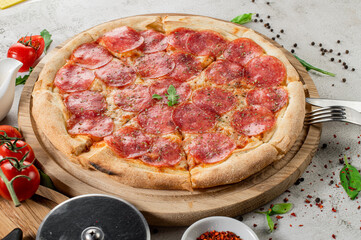 Fresh tasty pizza with meat, sausages, salamy and ham on white concrete background