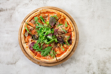 Fresh pizza with meat and vegetables on the white concrete background