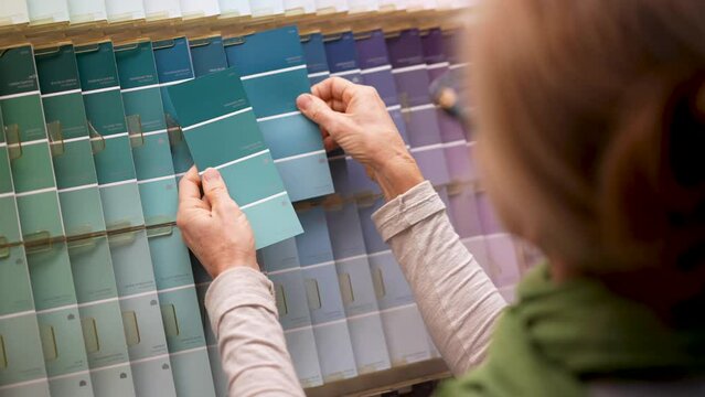 Slow motion closeup of mature woman looking at paint chips in a hardware store. Concept of shopping experience for home improvement.
