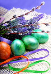Painted green and orange eggs with lavender and willow on a burlap background.