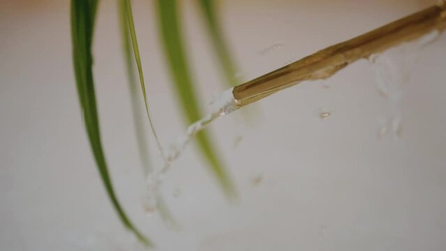 Water droplets flow on the handle of a golden spoon.