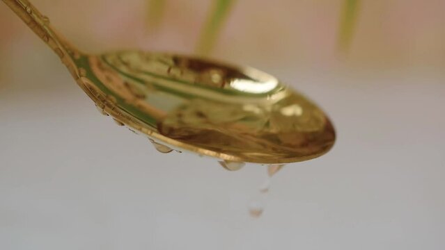 water drops pouring on golden spoon close-up blur background