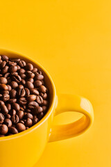 Cup of freshly brewed roasted coffee beans on yellow background