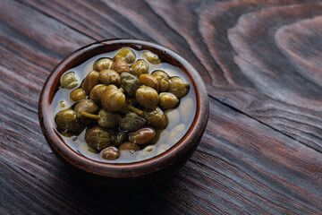 Pickled capers in brine. Clay cup full of capers.