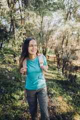 Self-confidence. Teenage girl looking at camera carrying backpack with serene smile in forest. 