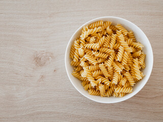 Spirelli / Fusilli / Spiral-Pasta in einer weißen Porzelanschale auf einem Echtholztisch bei...