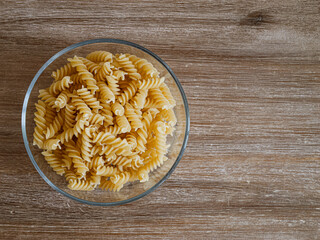 Spirelli / Fusilli / Spiral-Pasta in einer Glasschale auf einem Echtholztisch bei natürlichem Licht