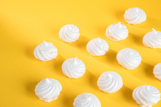 "Suspiros" or meringue, sweet made with egg whites, sugar and a few drops of lemon on a yellow background.