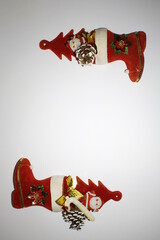 Botas rojas con piñas y chucherìas de Papà Noel para decoraciònes de la Navidad, formando en sus extremos una guirnalda con espacio, forma un original y bello diseño con fondo blanco