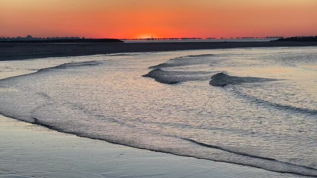 Lever de soleil et reflets de la lumi&egrave;re orange sur les vagues