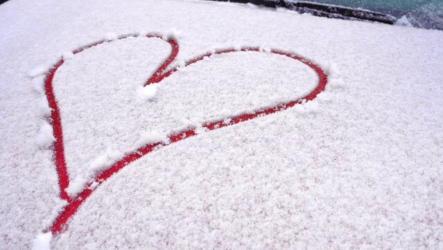 finger-drawn heart in the snow. Painted red heart on the snow-covered hood