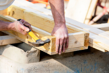 Carpenter hammering nail into the wood by hammer. Joiner with hammer and nail close-up