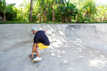 Skateboarder wearing yellow shorts riding carving in bowl skate park.