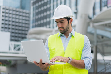 Man engineer standing on construction site. construction manager using walkie talkie. Engineer working on outdoor project and control with laptop