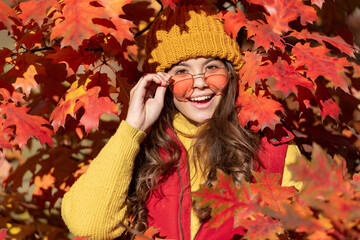 happy teen girl in sunglasses at autumn leaves on natural background