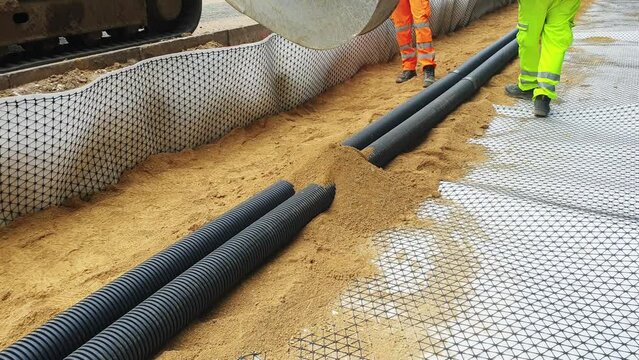 Groundworkers installing new electric ducts during roadworks	