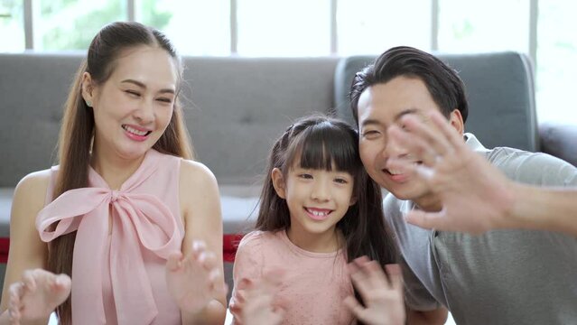 Happy Asian family staying together and waving a hands to camera.