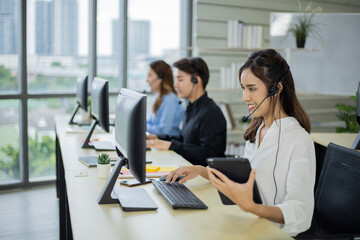 Side view of woman call center with headsets using computers in the office.