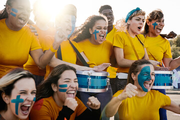 Crazy multiracial football fans celebrating in the crowd watching the game at sport stadium -...