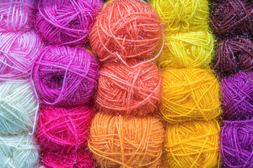 Bright multicolored balls of wool yarn with glitter for knitting. The concept of needlework and knitting.