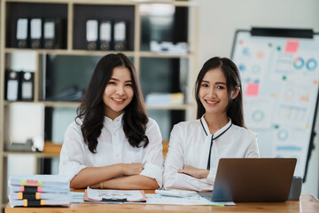 Portrait of beautiful asian businesswoman holding cup of coffee, smiling and looking at camera while sitting at office desk.