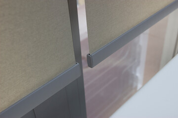Roller blinds on the window closeup, sand-colored material, silver bottom rail. The distance...