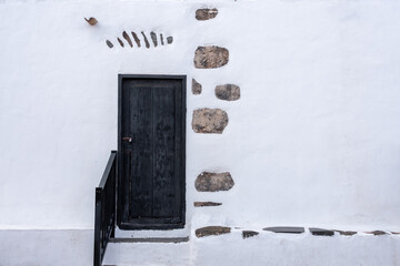 Rustic black wooden door in weathered white wall