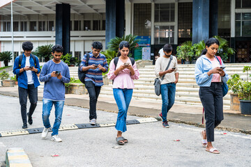 group of students busy checking result or using on mobile phone at college campus - concept of social media, smartphone addiction and technology. - obrazy, fototapety, plakaty