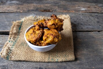 Masoor Dal Pakoda or Red Lentil Vada in a White Bowl on Burlap Fabric Isolated on Wooden Background with Copy Space