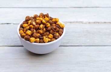 Roasted Chickpea  or Garbanzo Bean Coated with Spices, Salt and Chili Powder in a Bowl Isolated White Wooden Background with Copy Space, Also Known as Bengal Gram or Egyptian Pea