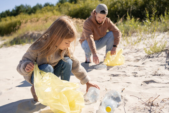 happy family activists collecting plastic waste on beach. Volunteers help to keep nature clean up and pick up garbage. 