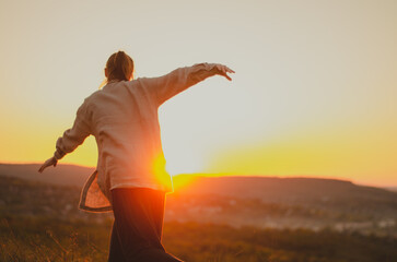 Woman doing intuitive movement on hill at sunset